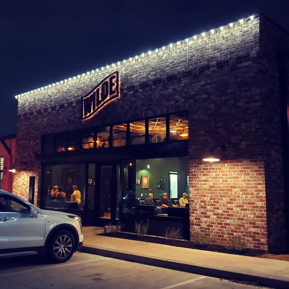 Wilde Cigars + Bar storefront at night with illuminated WILDE marquee in Burleson, Texas
